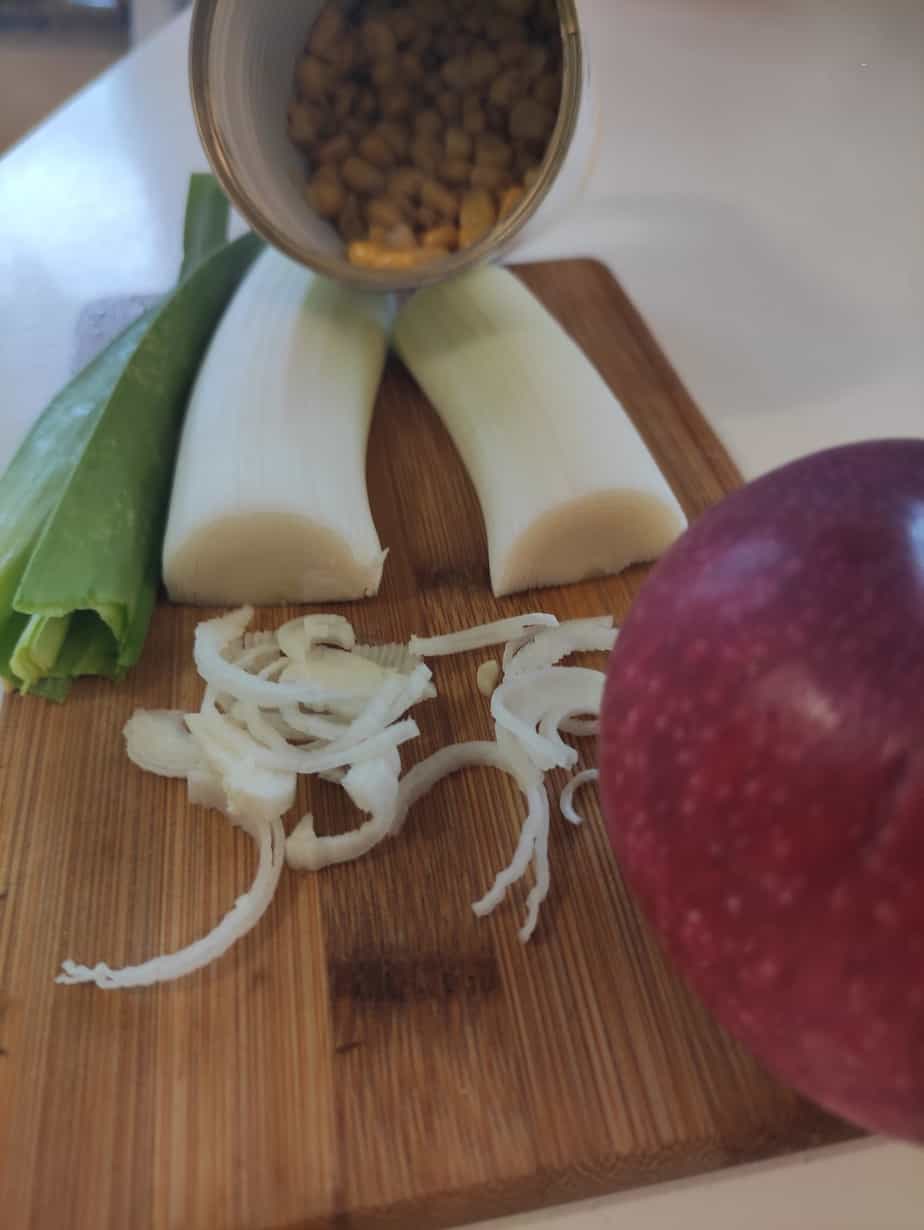 apples, leeks on a chopping board.