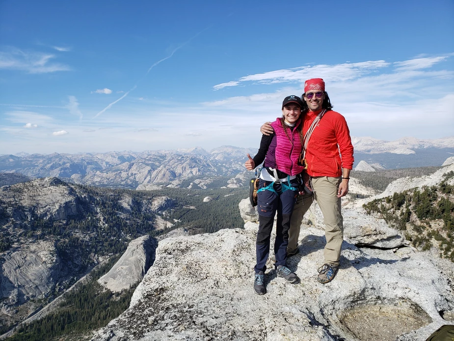 two people standing on top of a mountain with mountains in the background