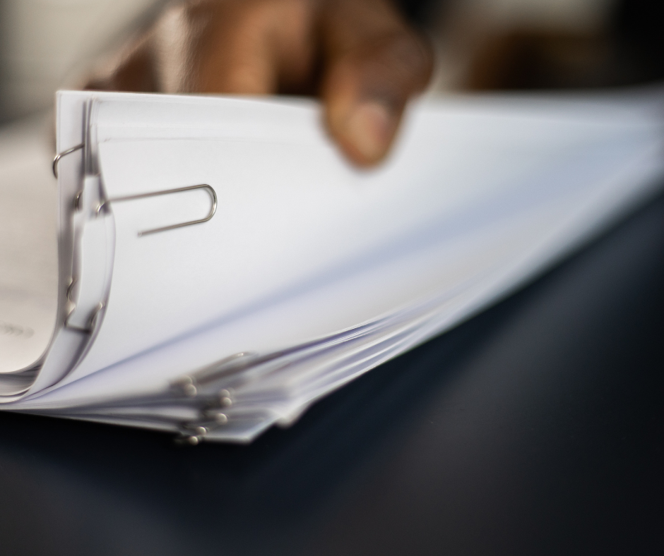 A hand flipping through a stack of papers