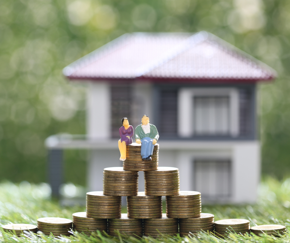 Action figures of a married couple sitting on a stack of coins with a house in the background