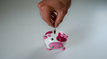 mano metiendo dinero en alcancía / plan de ahorro