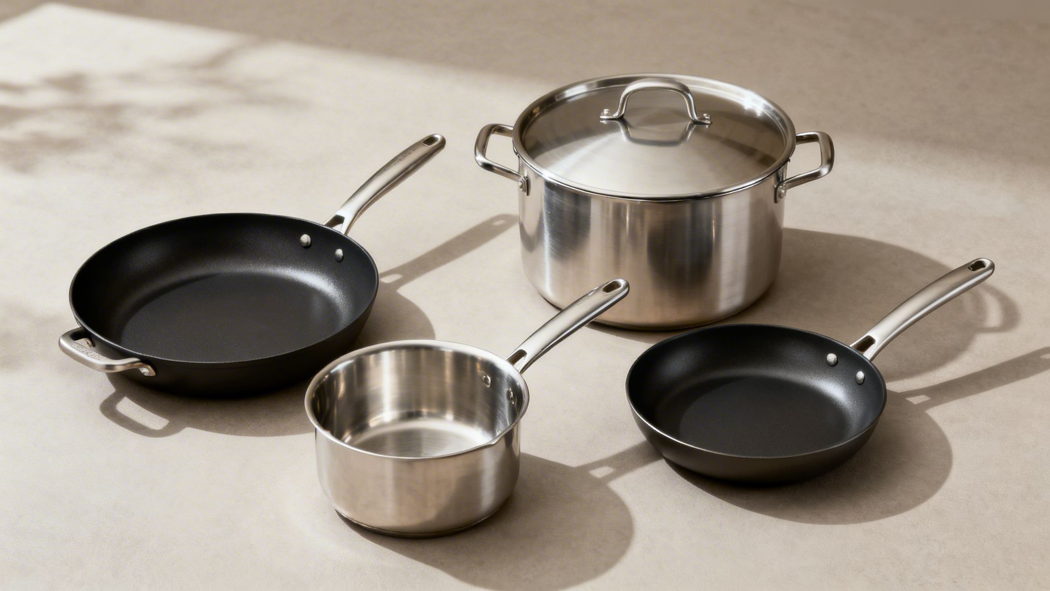 A collection of silver and black cookware, including a stock pot, saucepan, and two frying pans.