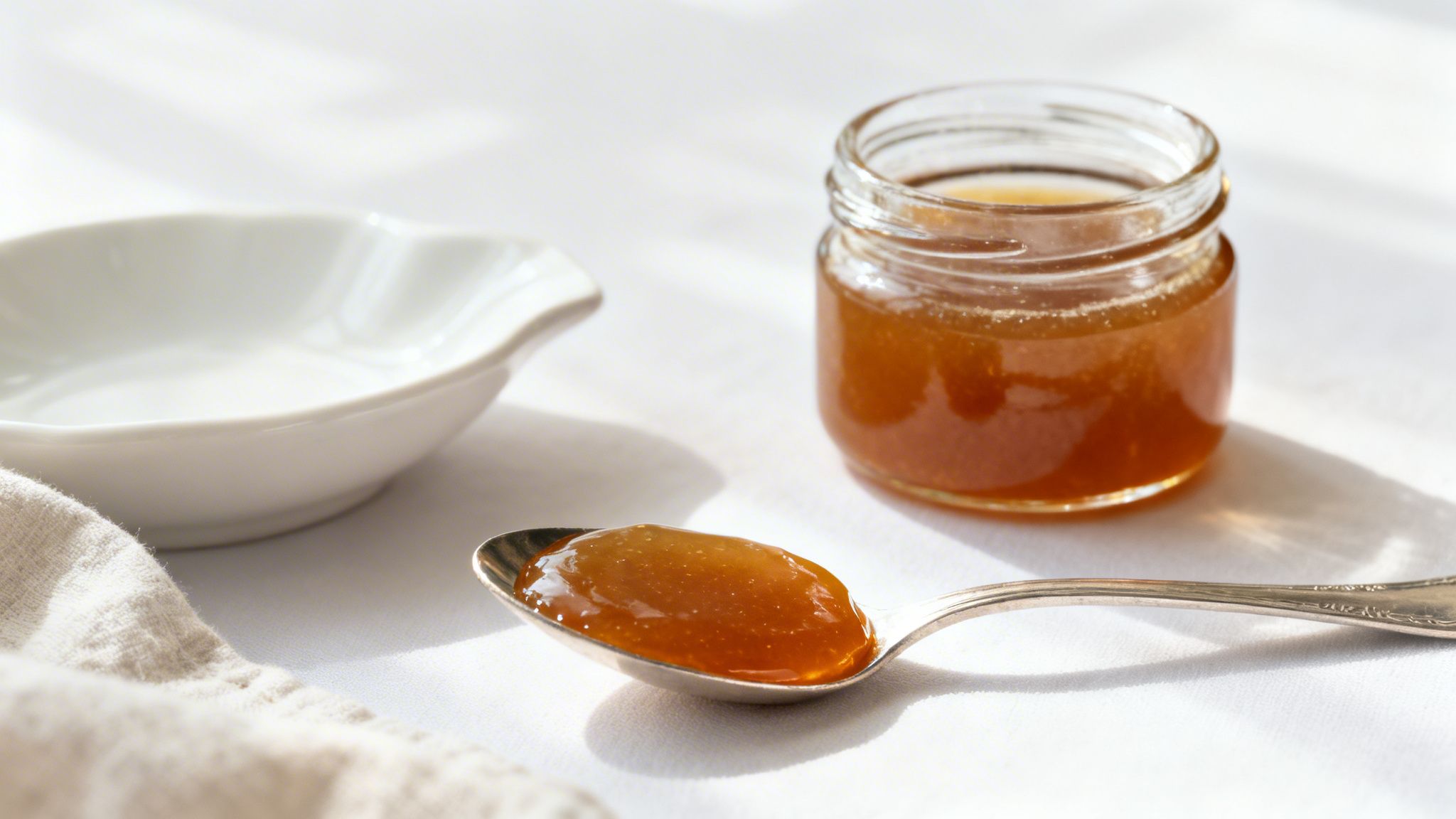 A spoon holding a dark, concentrated gel-like substance, reminiscent of bone broth concentrate.
