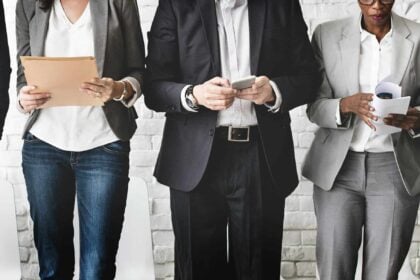 a group of people standing in front of a white brick wall