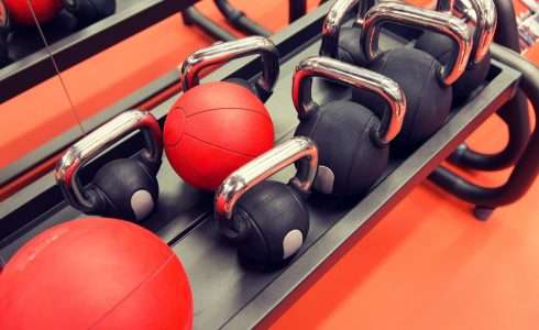 Kettlebells neatly arranged on a gym rack with red exercise balls in the background, in a Meridian, Idaho gym specializing in naturopathic medicine approaches.