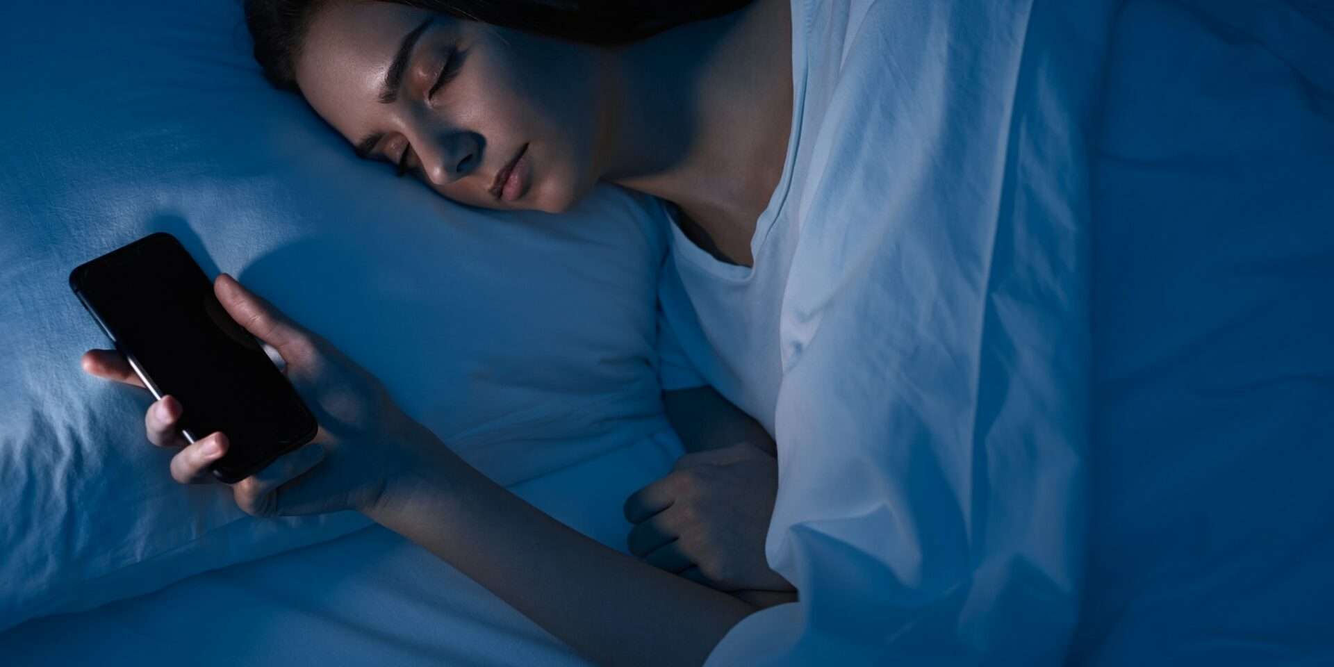 Woman sleeping with smartphone in bed