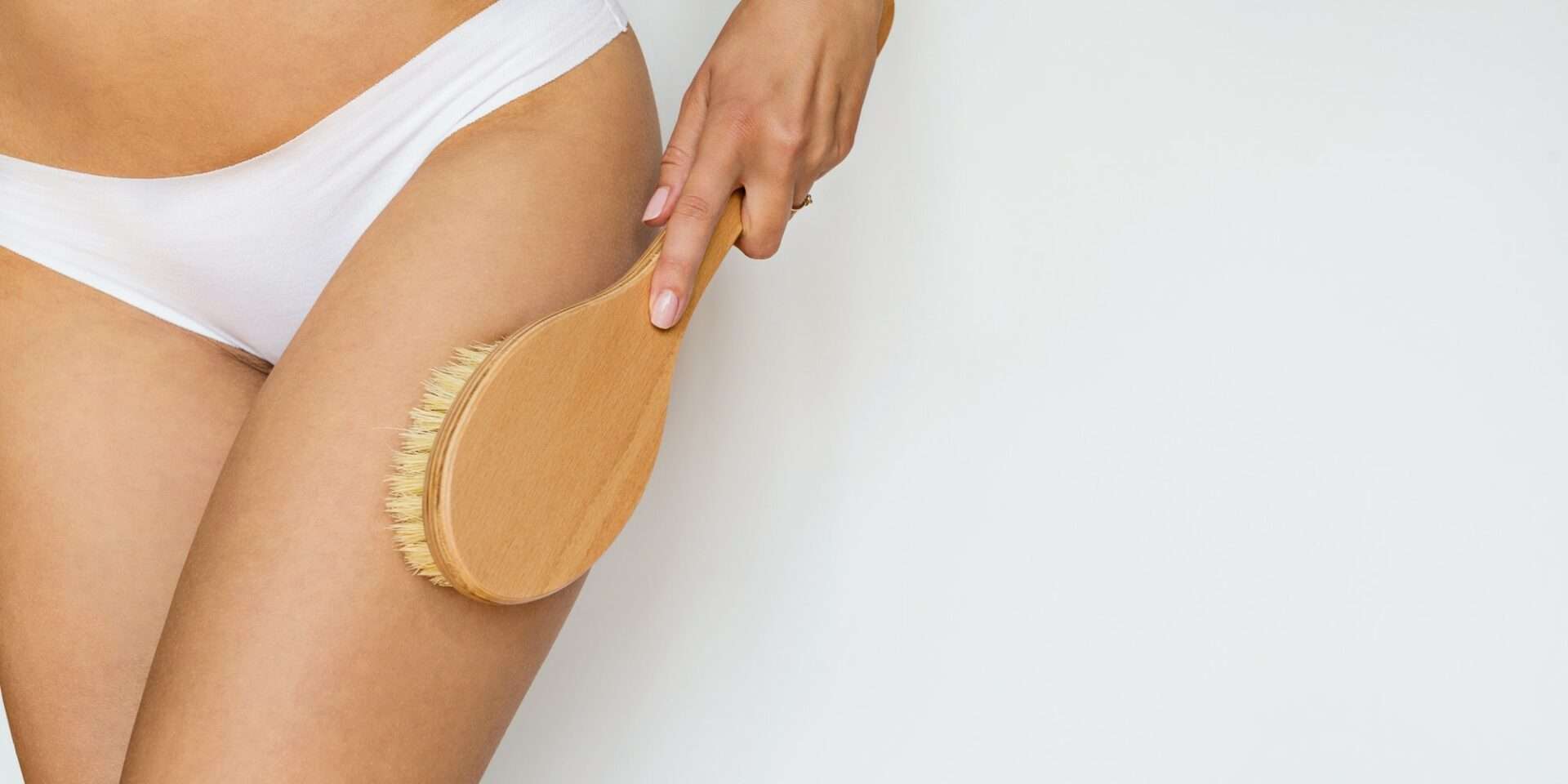 Woman using massage brush for skin health.