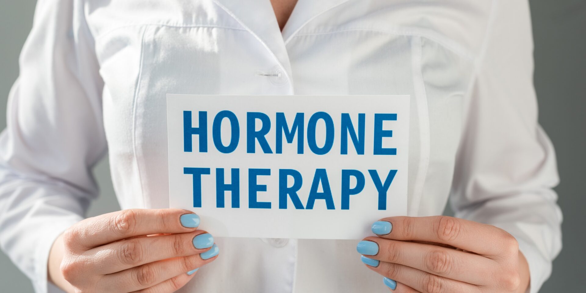 Cropped view of doctor holding card with hormone therapy lettering isolated on grey