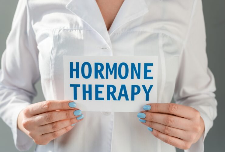 Cropped view of doctor holding card with hormone therapy lettering isolated on grey