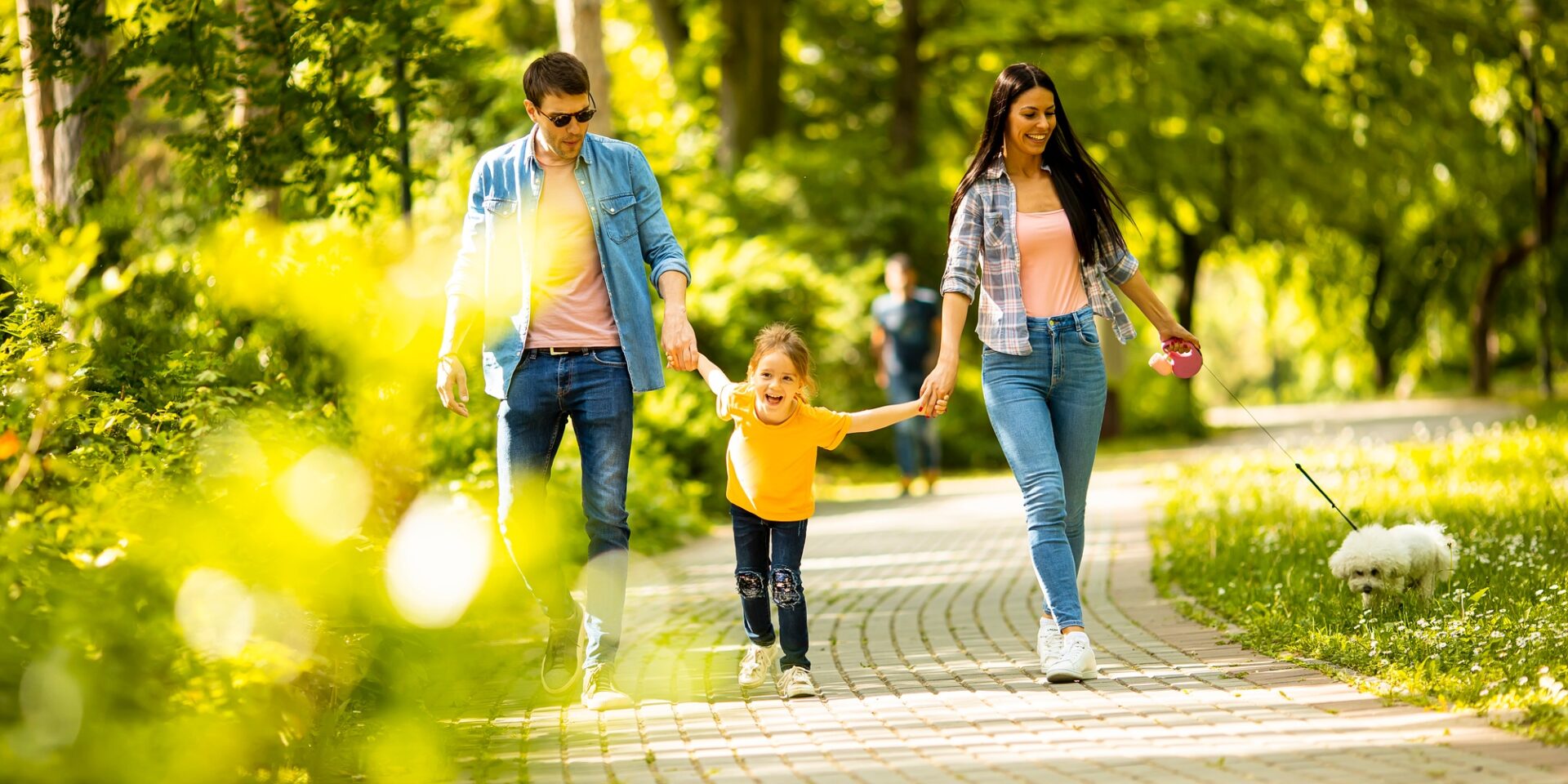 Happy family with cute bichon dog in the park