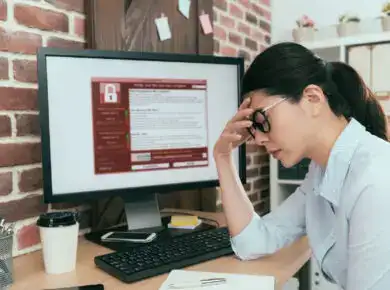 Ransomware - ATECHSO - Managed IT Company Concerned individual at a computer workstation with a security warning on the screen, indicative of a cybersecurity issue, data breach, or critical error requiring urgent attention.