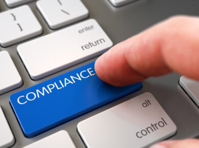 blog-3 - ATECHSO - Managed IT Company Finger pressing a blue 'COMPLIANCE' button on a grey keyboard, highlighting the importance of regulatory compliance in business practices and corporate governance.