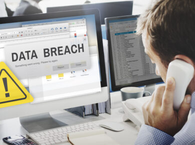 blog2 - ATECHSO - Managed IT Company Concerned businessman on the phone viewing a computer screen with a 'Data Breach' alert and caution symbol, representing urgent cybersecurity issues in the workplace.
