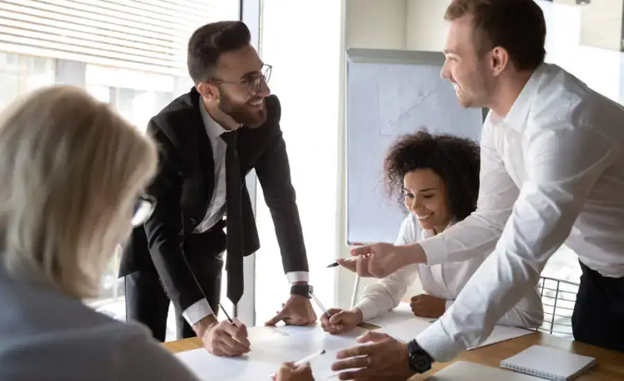 Enthusiastic business team engaged in a lively discussion around a conference table, signifying collaborative teamwork, corporate strategy meetings, or brainstorming sessions.