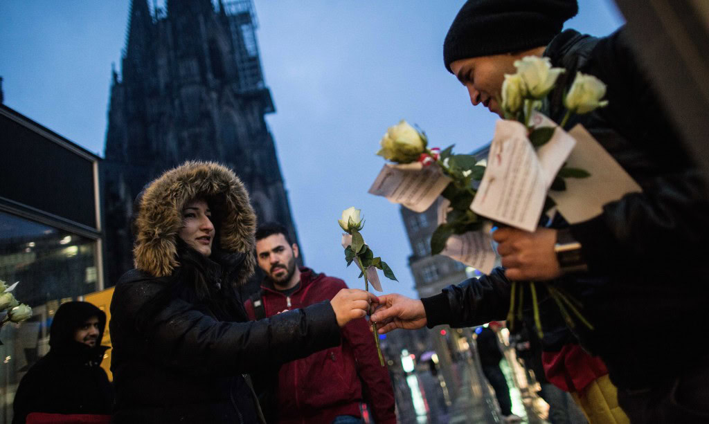 Des membres d'une association germano-tunisienne distribuent des fleurs aux passants devant la gare de Cologne, le 7 janvier
