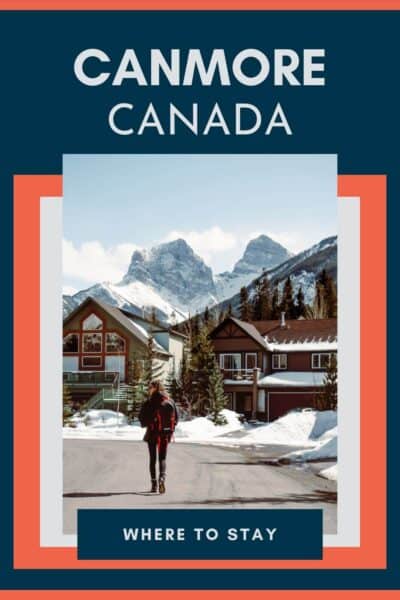 Person walking along the street towards some cabin style houses and mountains.