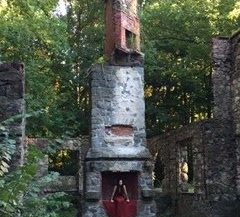 woman in red dress sitting in chimney of old destroyed mansion