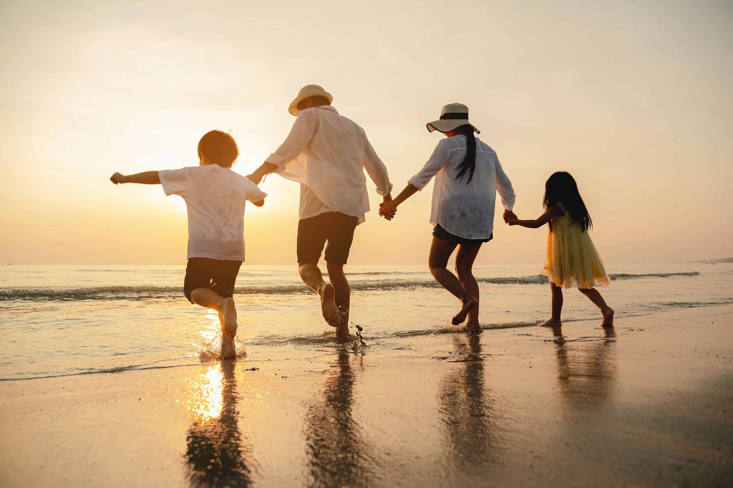 Family holding hands on the beach on a family vacation in Del Mar Beach CA