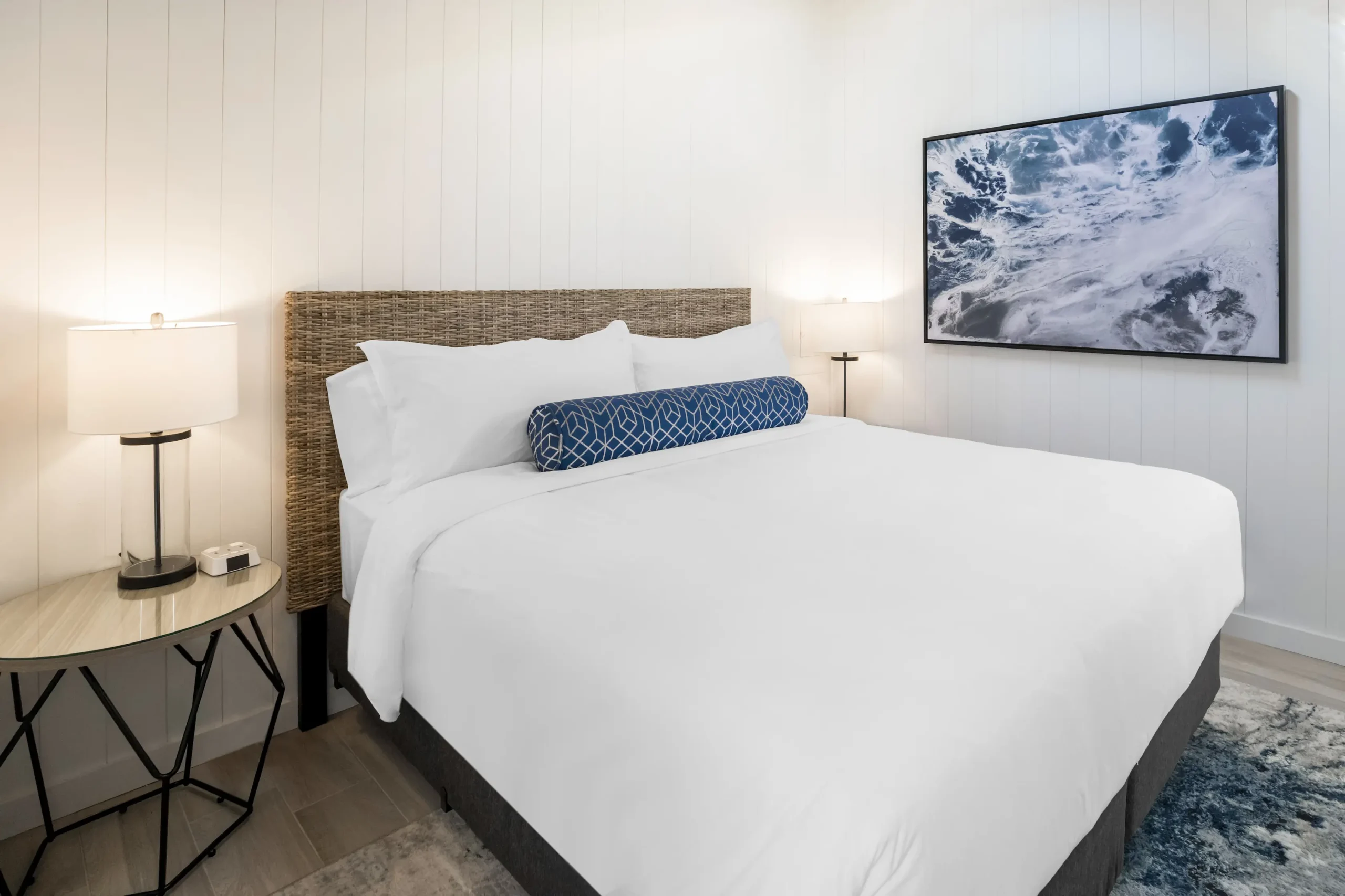 beach cottage guestroom. Bed with blue accent pillow and ocean artwork