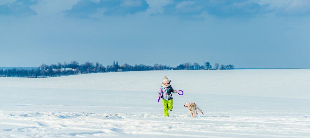 Girl running with dog in snow