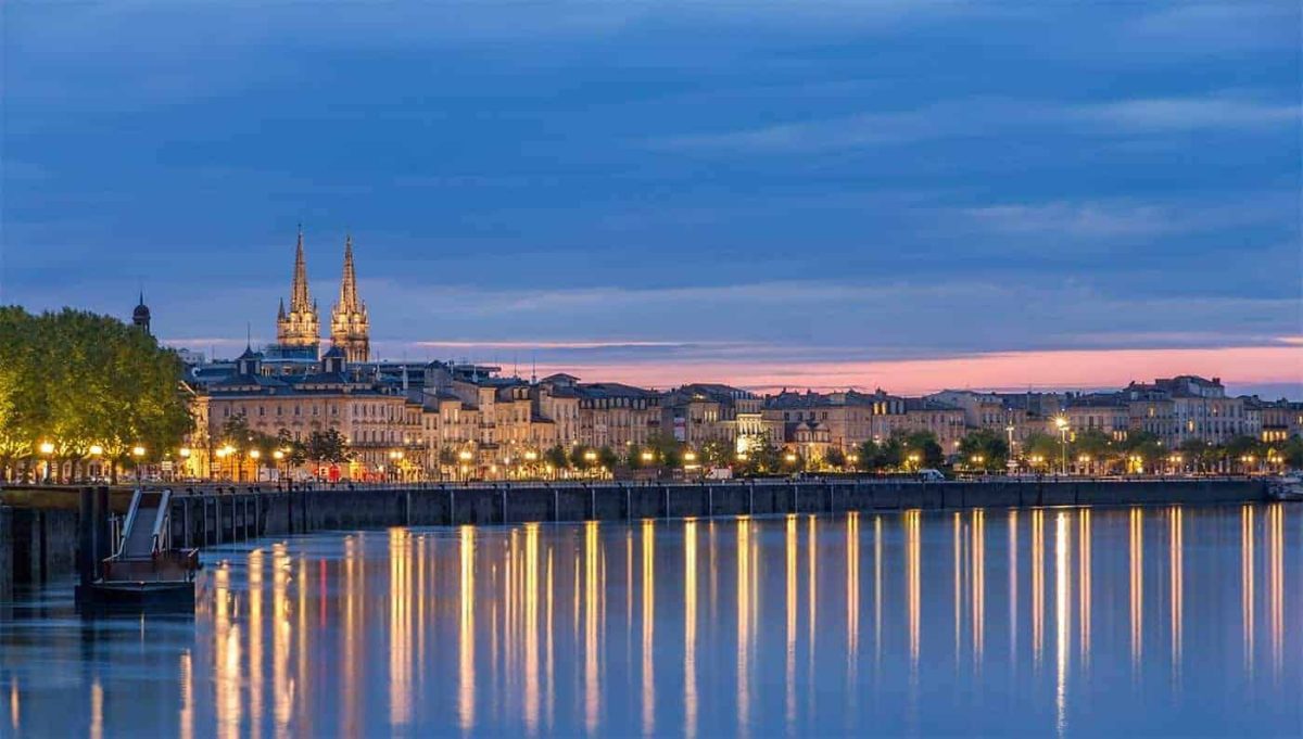 Bordeaux City, a lit up street at night along the river.