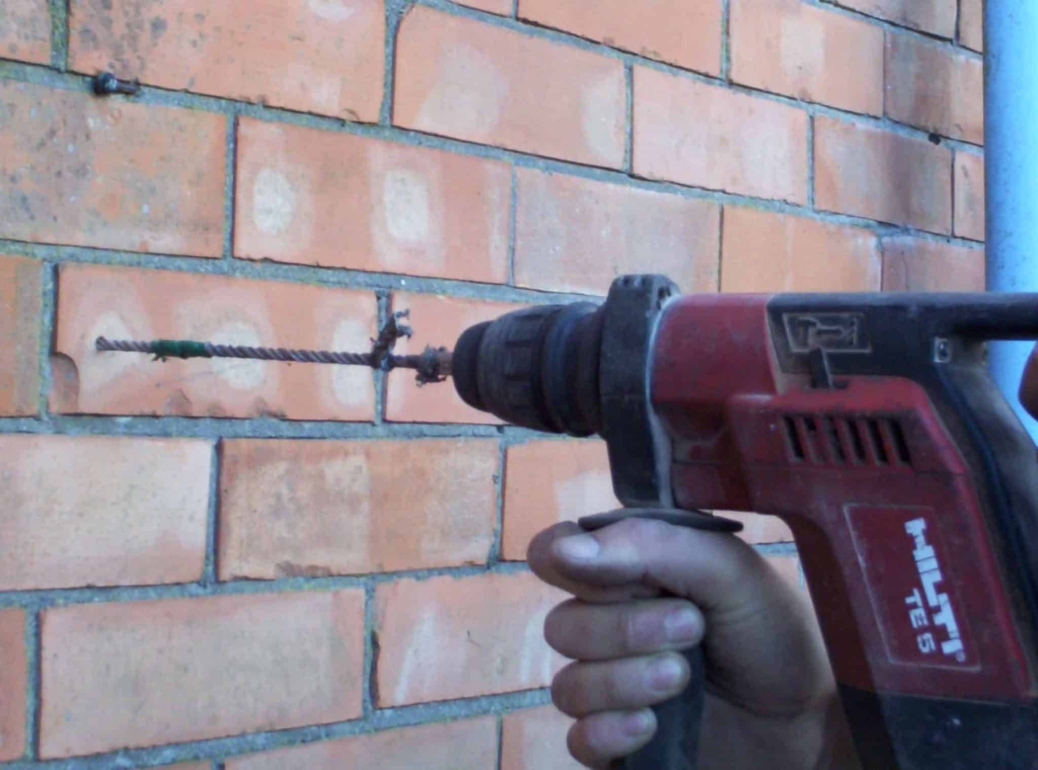 Drilling pilot hole in brick wall for cavity wall tie