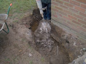 Ground around building being dug prior to foundation repairs