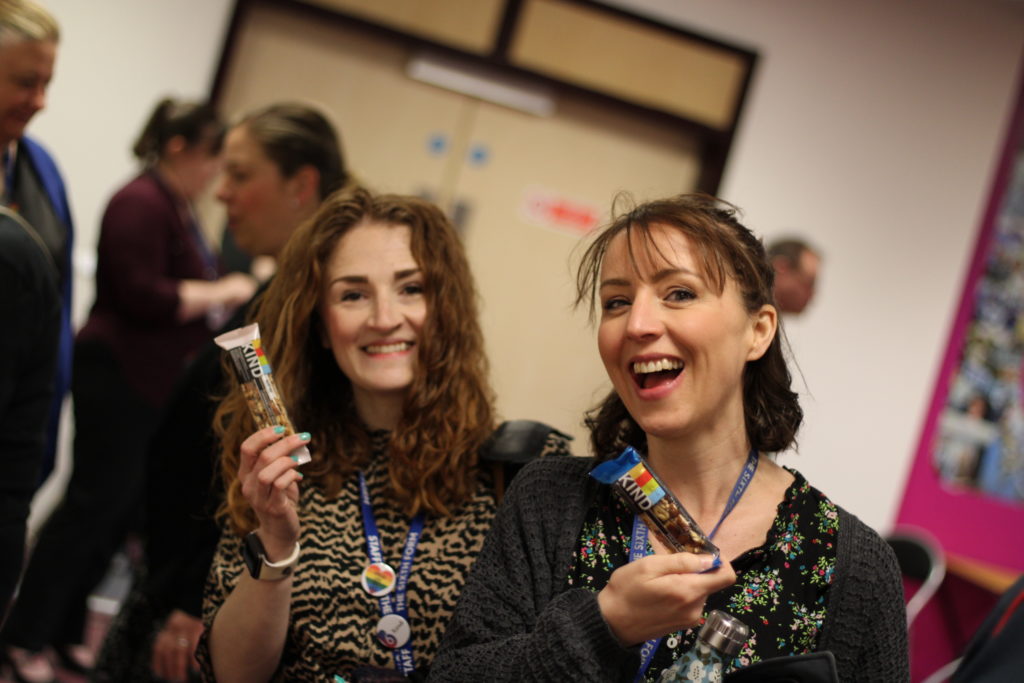 Two happy women holding KIND Bars in an office environment